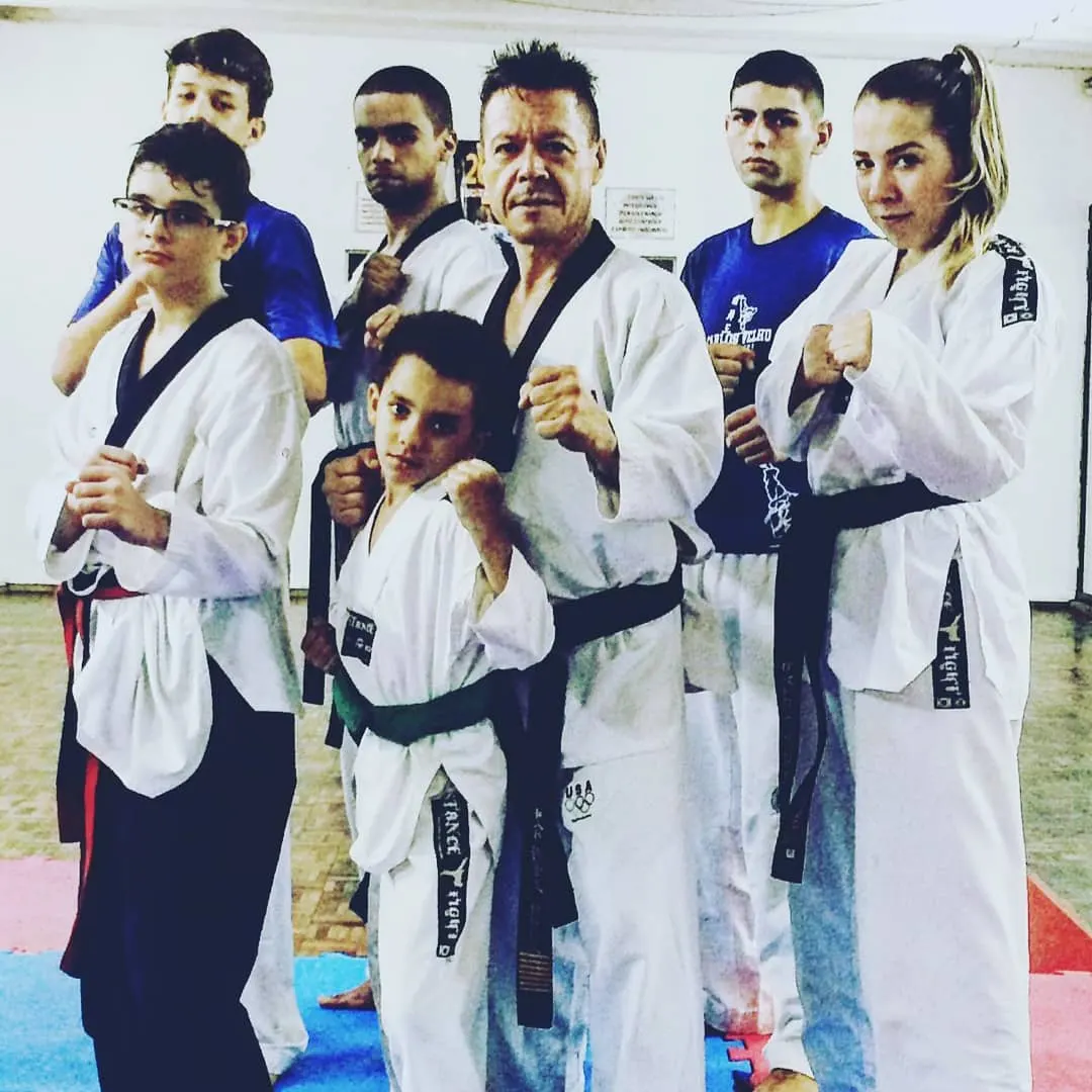 Mestre Paulo Ribeiro em guarda no centro de sua equipe de Taekwondo, com alunos de várias idades