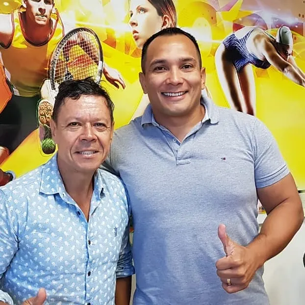 Mestre Paulo Ribeiro ao lado do presidente da FESPORTE, Rui Godinho, que faz sinal de positivo diante de um painel com imagens de esportes