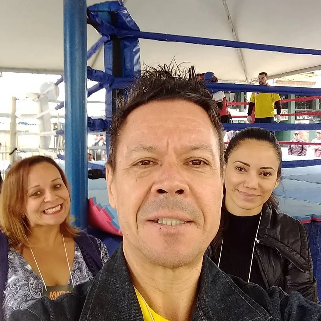 Mestre Paulo Ribeiro com duas diretoras da FECAMTT ao lado do ringue azul de Muaythai
