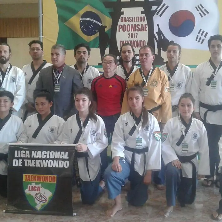 Atletas e mestres da Liga Nacional de Taekwondo diante do painel do Brasileiro de Poomsae 2017, com as bandeiras do Brasil e da Coreia